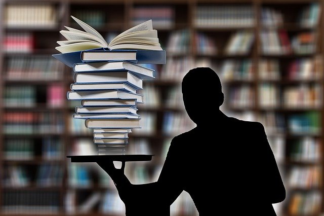 silhouette of man holding a stack of books on a tray